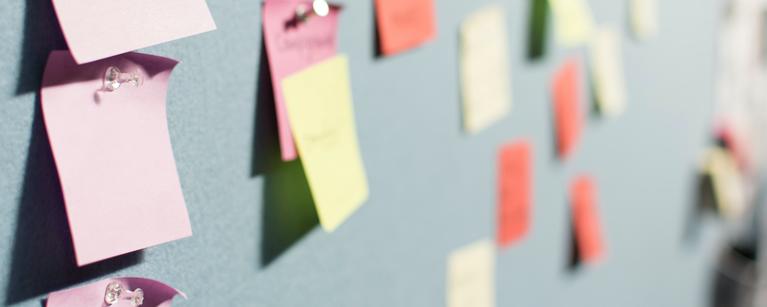 Different coloured post it notes attached to a wall
