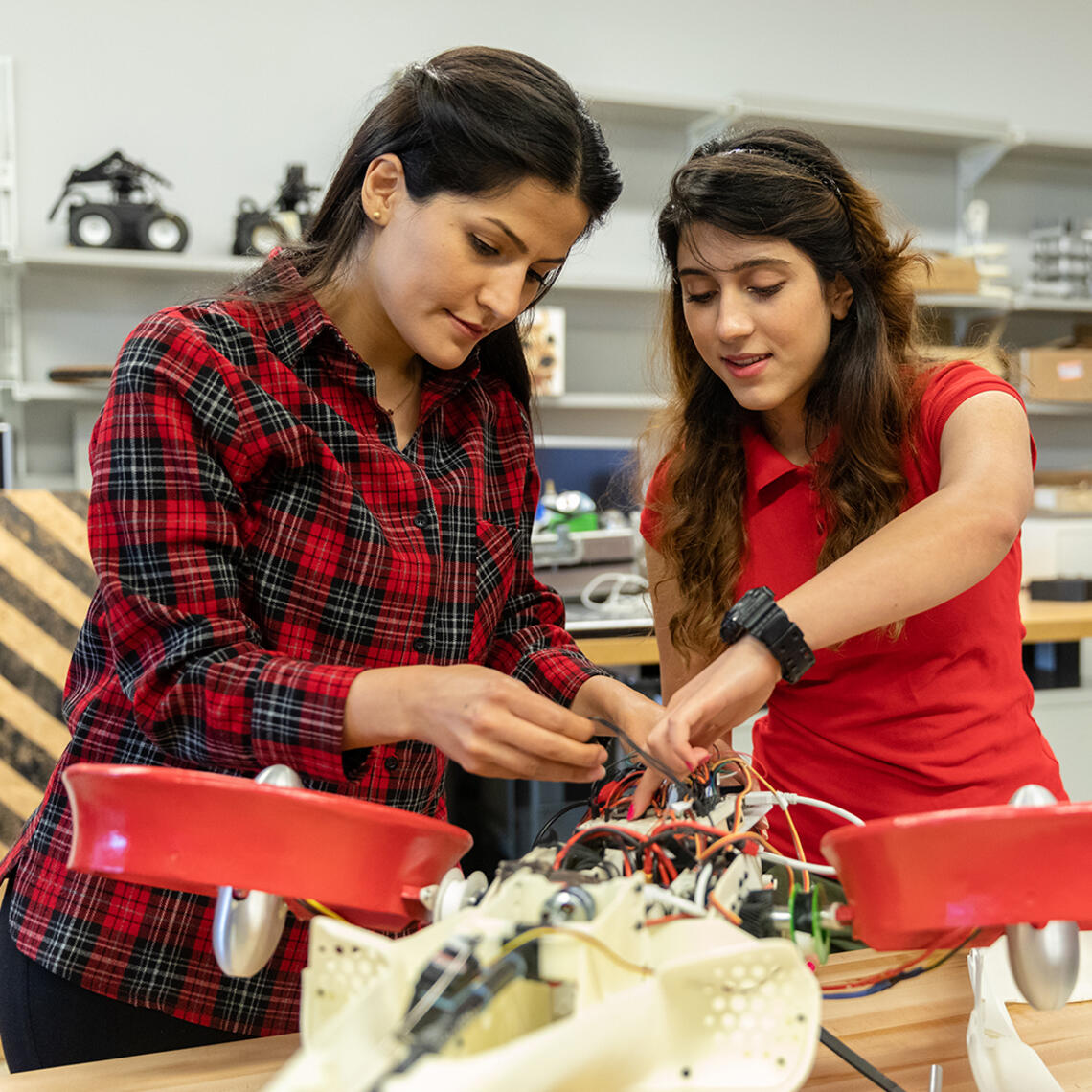 Two people work on a device at a workbench