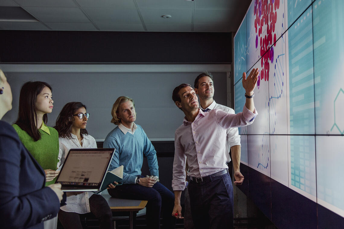 People discussing industry needs in front of a multimedia wall.