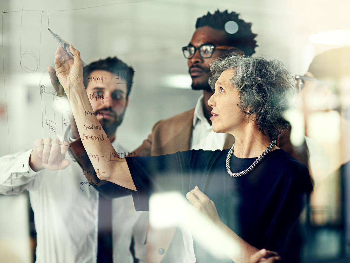 Group of researchers brainstorming with notes on a glass wall in an office.