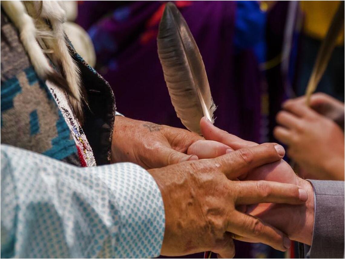 Hands embracing with feathers and beadwork