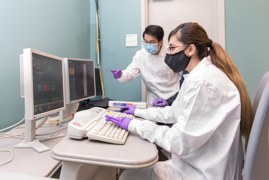 Two people working on a computer with multiple screens