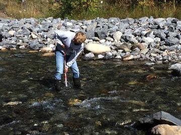 A student takes depth measurements in the creek.  
