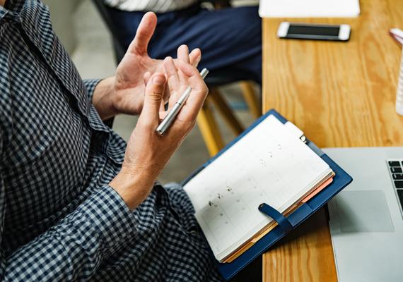 Person holding pen while sitting 