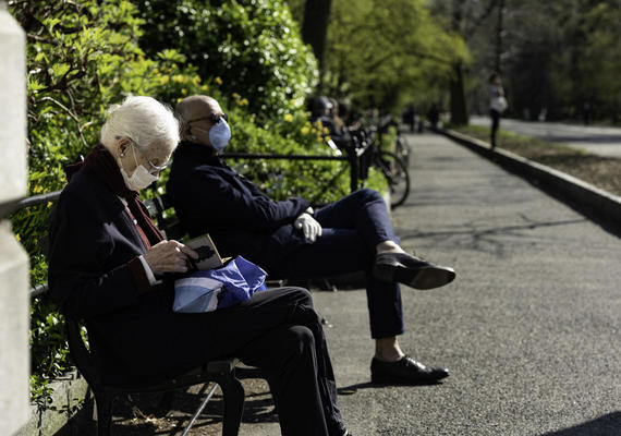 Older adult on park bench with mask on