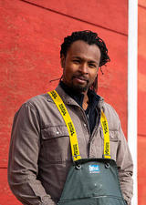 Tatenda Mambo, PhD, standing in front of a farm building.