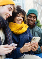 people sitting together, smiling, on their cell phones